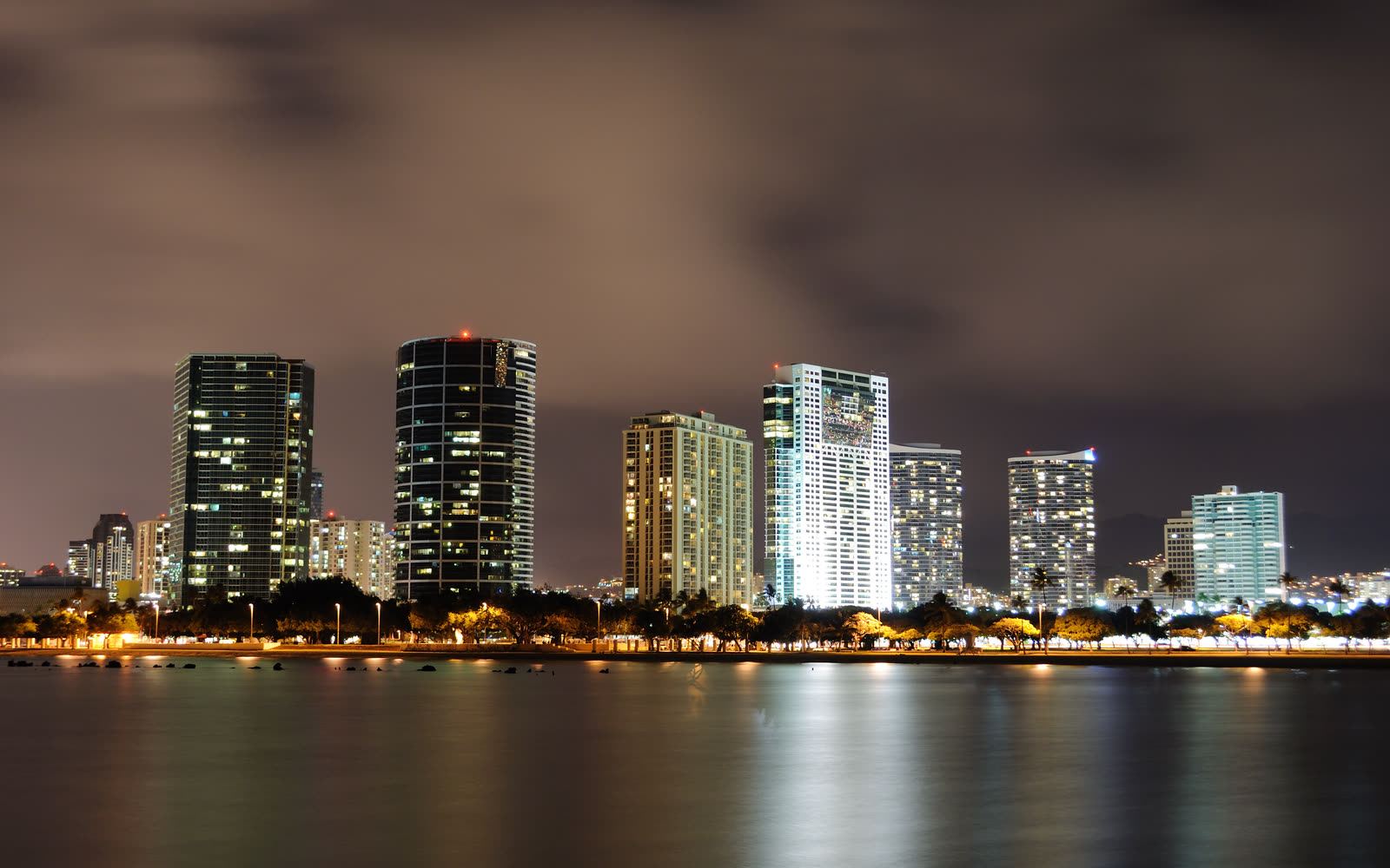 Kakaʻako and Ala Moana towers lit at night across the water