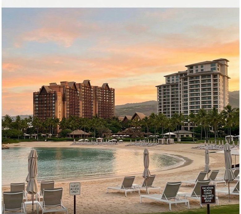 Resort towers above a man-made lagoon at sunset, beach chairs in the foreground