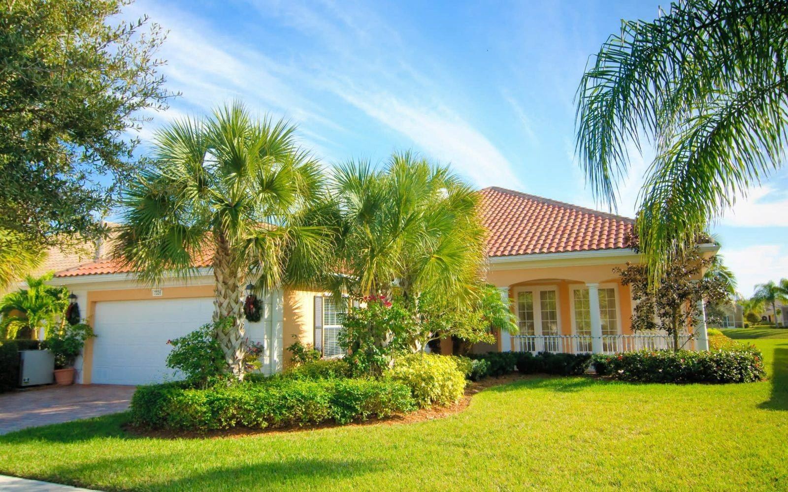 A single-family home behind a palm-lined lawn