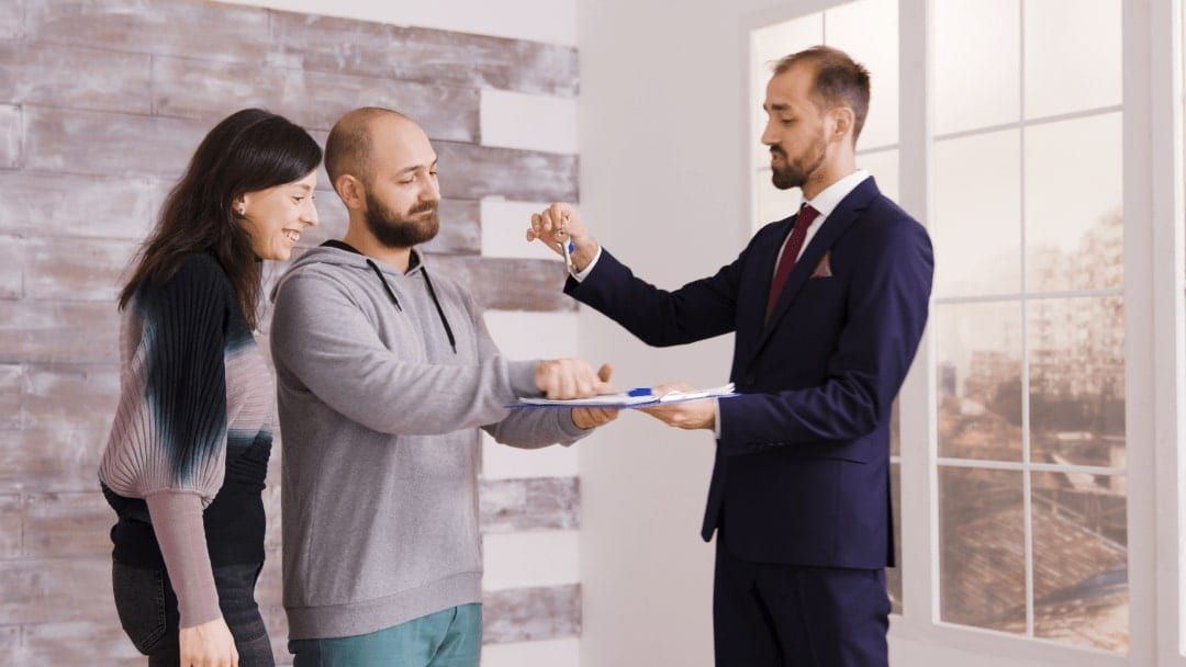 An agent handing house keys to a couple